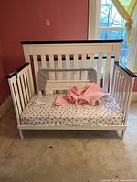 Full view of white child’s daybed with mattress and bedding