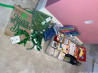 Lot overview showing tissue paper packs, shredded filler, St. Patrick’s décor, plastic bin with greeting cards