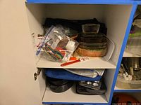 Cabinet shelf with various items showing glass dishes, utensils, bags