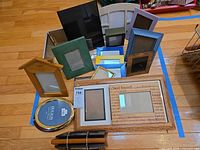 Lot overview showing majority of frames arranged on floor including collage plaque, house frame, oval Holson frame and assorted rectangular frames