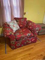 Front view of red floral upholstered armchair with throw pillow