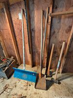 Group of five long-handled tools leaning against wall