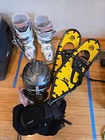All items grouped: ski boots, snowshoes, helmet (excluded), goggles, gloves