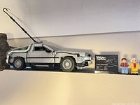 Side view of assembled DeLorean with plaque and minifigures on shelf
