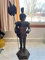 Full view of metal knight statue with spear, shield, base