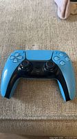 Front view of blue Sony DualSense controller on fabric surface