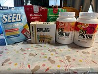 Front view of all protein containers and box on table