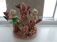Front view of Capodimonte porcelain figurine with cherubs holding rose garland