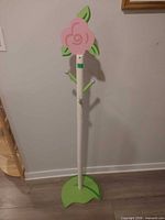Full view of white and green coat hanger with pink flower top
