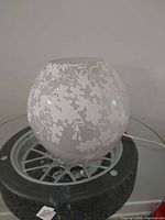Side view of frosted glass globe lamp showing floral pattern