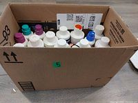 Box filled with multiple white plastic paint/ink bottles