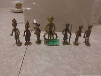 Front view of all seven bronze-tone tribal figurines lined in a row