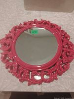 Front view showing round glass and pink ornate frame