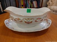 Side view of gravy boat resting on underplate showing floral and gold decoration