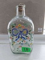Front view of bottle showing bow and floral painting
