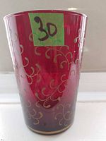 Front view of red glass vase showing gold vine ornamentation and overall shape
