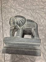 Front angled view of carved stone elephant showing base and engraved details