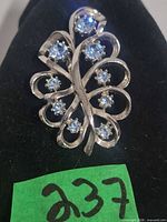 Front view of silvertone brooch with blue rhinestones on black background