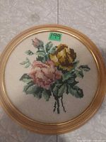 Front view of round framed needlepoint showing floral design