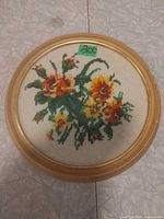 Front view of floral needlepoint in round frame
