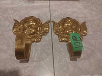 Front view of both brass cherub wall hooks