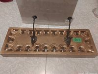 Front view of carved wooden board with two attached metal hooks
