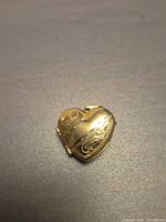 Front view of heart-shaped gold locket showing engraved design