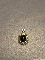 Front view of 14K gold pendant showing onyx center and pearl halo