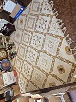 Full view of cream and mustard geometric wool rug on floor with fringe visible