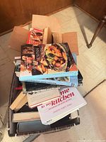 Box of assorted cookbooks stacked vertically and horizontally