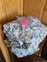 Folded floral comforter with shams visible in bag