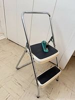Full view of chrome two-step folding stool showing both steps and handle