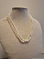 Full view of triple-strand freshwater pearl necklace displayed on bust form