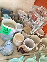 Group view of glass canister, mugs, pitchers and cruet
