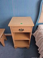 Front view of light maple veneer nightstand showing drawer with brass-tone pull and two open shelves