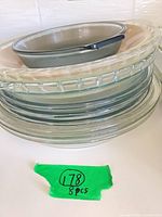 Stack of eight round baking dishes showing glass and ceramic pieces