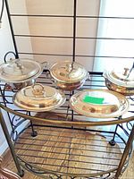 Five silver-plated covered serving dishes displayed on rack