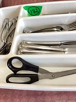 flatware pieces arranged in white tray with scissors visible