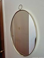 Oval gold/brass metal framed wall mirror with top hanging ring