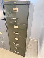 Full view of dark green four-drawer metal filing cabinet
