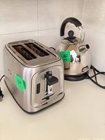 Front and side view of stainless steel 2-slice toaster with attached power cord (kettle in background not included)