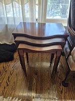 Front view of three nested tables showing wavy edges and leg design