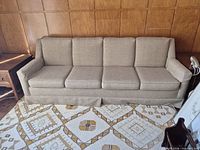 Full view of beige/tan four-seat skirted sofa