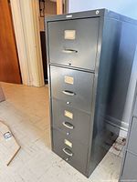 Full view of gray four-drawer vertical file cabinet showing handles and label frames