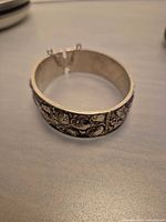 Wide sterling hinged bangle showing interior and safety chain