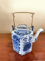 Full view of hexagonal blue and white floral porcelain teapot with lid and swing handle