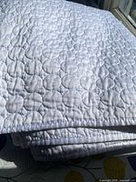 Folded white quilt showing satin sheen and circular quilting