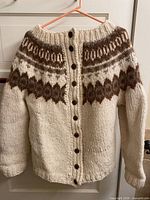Front view of cream wool cardigan with brown Nordic pattern and buttons