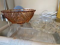 Side view of pink pressed glass bowl and clear divided dish