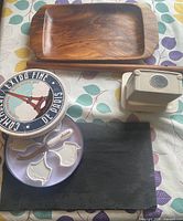All five items arranged: teak board top, butter dish top right, cheese knife set tin and ceramic markers left, slate board bottom, no flute visible